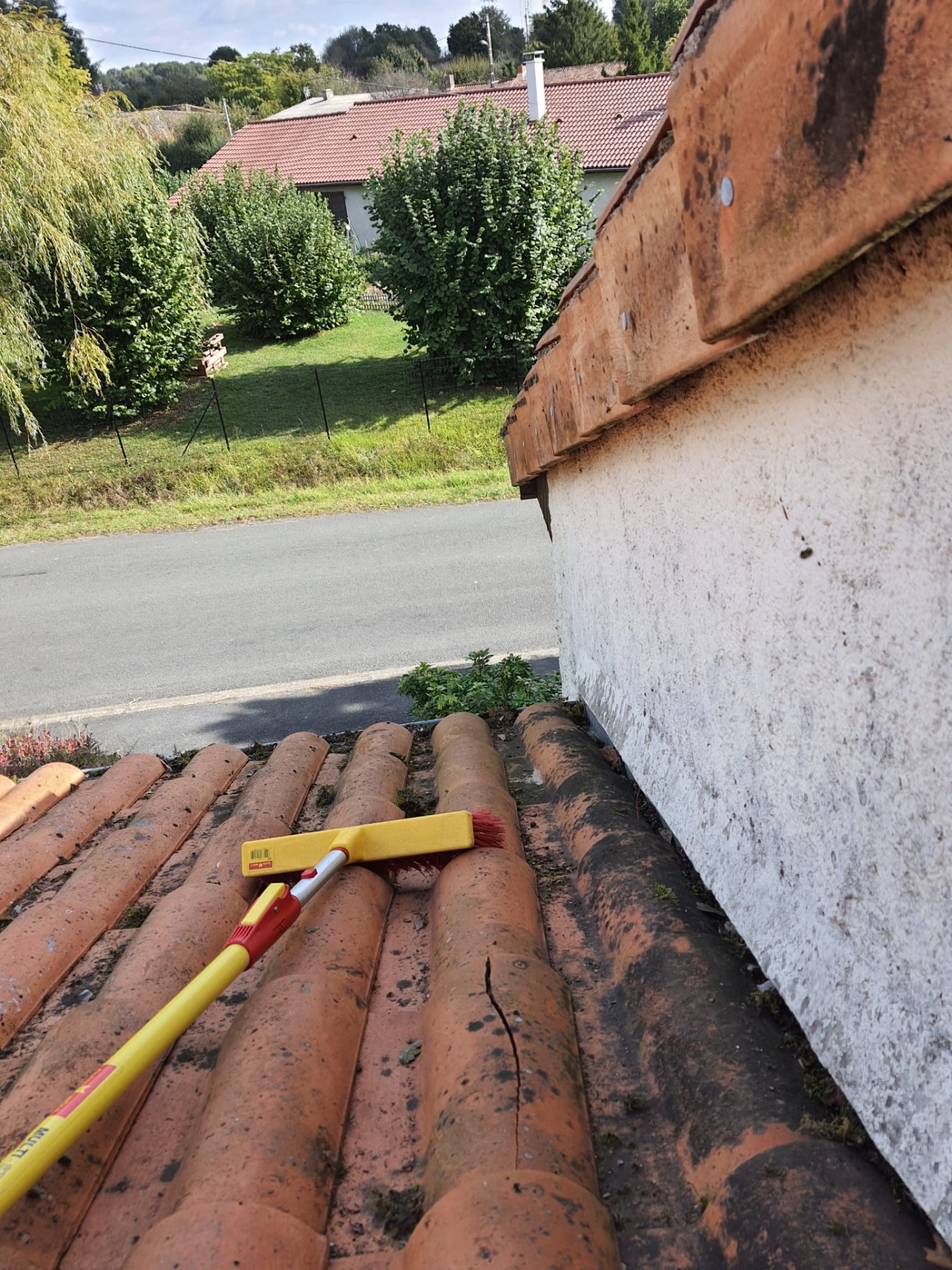 Brossage manuel de tuiles canal lors du nettoyage d'une toiture dans le Saumurois