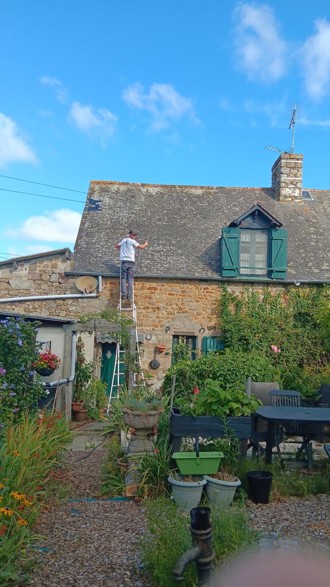 Démoussage d'une toiture en ardoise sur une maison ancienne en pierre