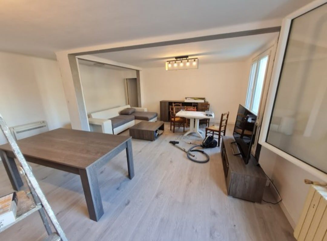 Séjour rénové avec murs peints en blanc et parquet clair posé