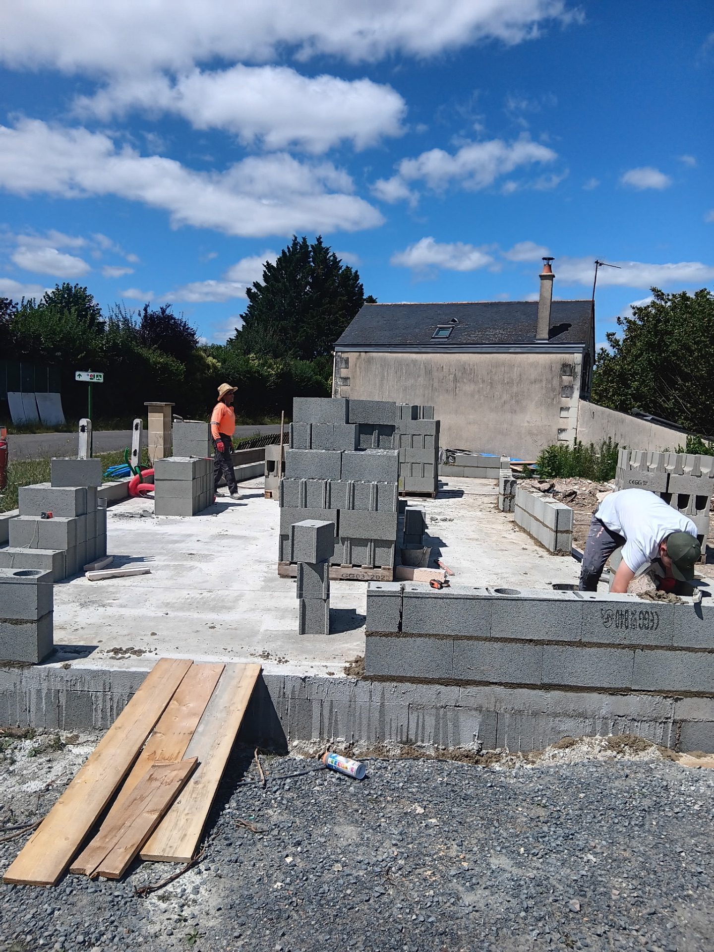 Dalle béton coulée et palettes de parpaings prêtes pour le montage des murs
